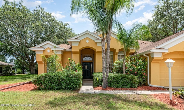 2703 Barrow Dr, Merritt Island, FL 32952 - mediterranean / spanish home featuring stucco siding, a front yard, an attached garage, and roof with shingles