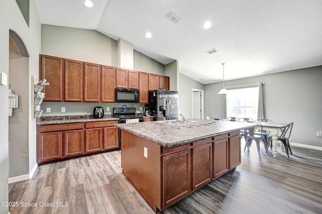 870 Buchanan Ave SE, Palm Bay, FL 32909 - kitchen with black appliances, light wood-style flooring, brown cabinetry, a kitchen island with sink, and baseboards