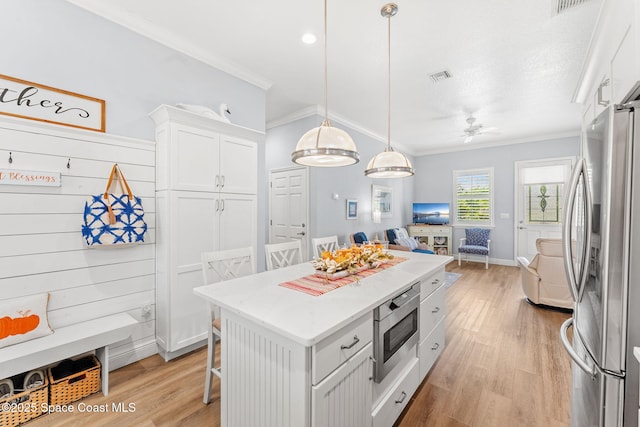 5853 Goldrush Ave, Grant-Valkaria, FL 32949 - kitchen with stainless steel appliances, open floor plan, crown molding, light wood-style flooring, and white cabinetry