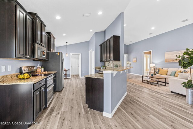 681 Dillard Dr SE, Palm Bay, FL 32909 - kitchen featuring stainless steel appliances, a peninsula, open floor plan, light wood-type flooring, and a breakfast bar area