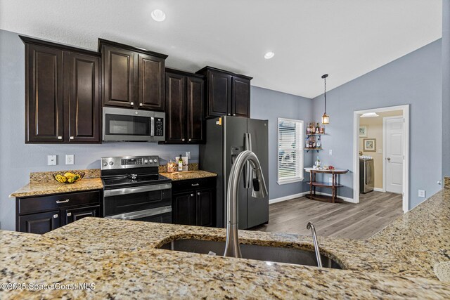 681 Dillard Dr SE, Palm Bay, FL 32909 - kitchen featuring stainless steel appliances, wood finished floors, a sink, vaulted ceiling, and light stone countertops