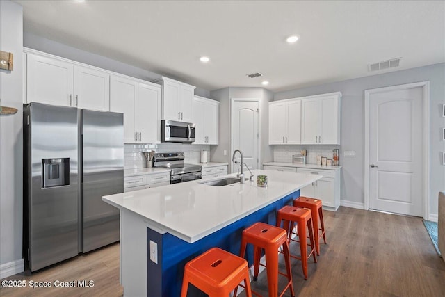1160 Larkspur St SE, Palm Bay, FL 32909 - kitchen featuring stainless steel appliances, a sink, wood finished floors, a breakfast bar, and backsplash