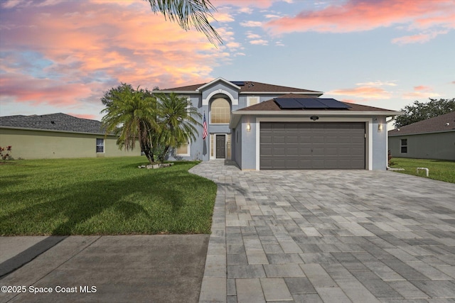 5060 Spinet Dr, Melbourne, FL 32940 - view of front of property featuring solar panels, a front yard, a garage, stucco siding, and decorative driveway