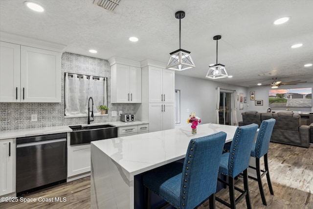 5060 Spinet Dr, Melbourne, FL 32940 - kitchen featuring stainless steel dishwasher, a sink, wood finished floors, open floor plan, and white cabinetry