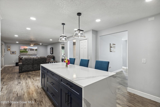 5060 Spinet Dr, Melbourne, FL 32940 - kitchen featuring wood finished floors, baseboards, recessed lighting, pendant lighting, and a kitchen island