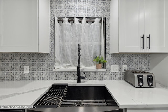 5060 Spinet Dr, Melbourne, FL 32940 - kitchen view of a sink, white cabinets, decorative backsplash, and light stone countertops