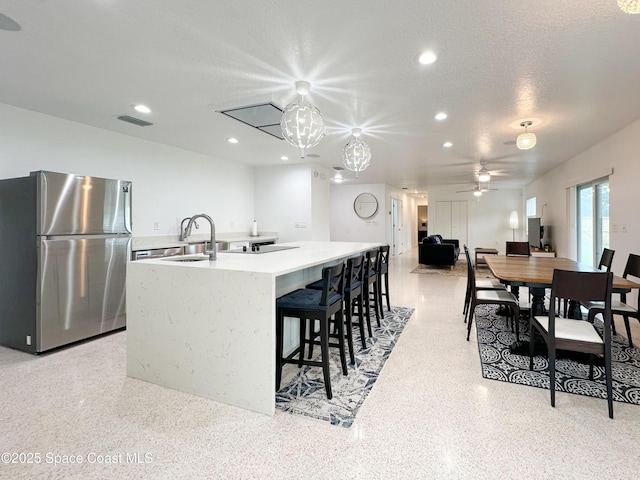 234 Micanopy Ct, Indian Harbour Beach, FL 32937 - kitchen with freestanding refrigerator, a sink, an island with sink, light countertops, and dark aggregate flooring
