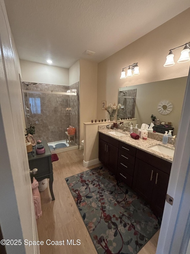 5908 Van Ness Dr, Melbourne, FL 32940 - full bath featuring a shower stall, double vanity, wood finished floors, toilet, and a textured ceiling