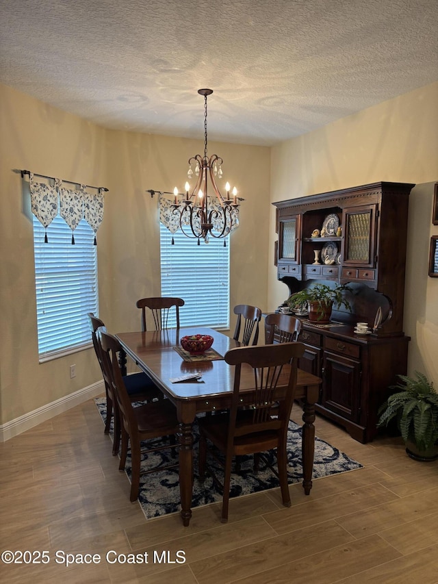 5908 Van Ness Dr, Melbourne, FL 32940 - dining area with a chandelier, a textured ceiling, light wood finished floors, and baseboards