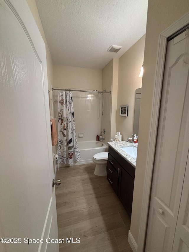 5908 Van Ness Dr, Melbourne, FL 32940 - bathroom featuring vanity, toilet, shower / tub combo with curtain, wood finished floors, and a textured ceiling