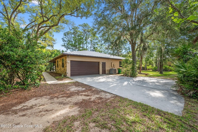 7001 Windover Way, Titusville, FL 32780 - view of side of home with stucco siding, driveway, a standing seam roof, a garage, and a metal roof