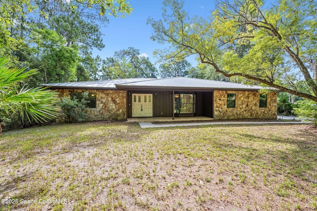 7001 Windover Way, Titusville, FL 32780 - view of front facade featuring stone siding, a standing seam roof, a metal roof, and a front yard