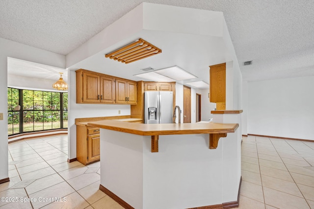 7001 Windover Way, Titusville, FL 32780 - kitchen featuring stainless steel refrigerator with ice dispenser, a textured ceiling, light tile patterned floors, light countertops, and a kitchen breakfast bar