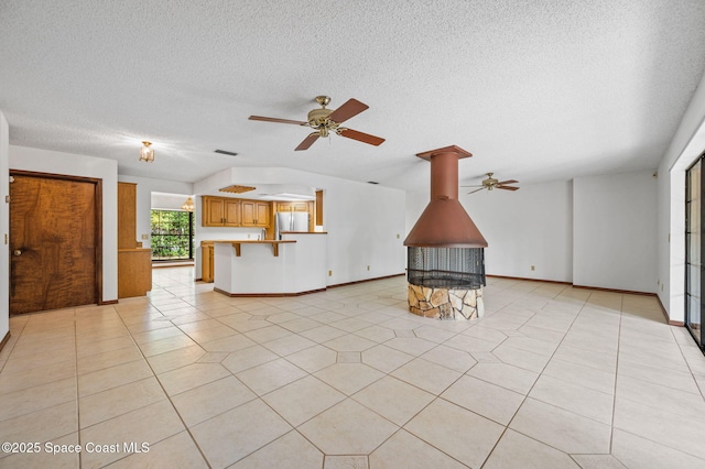 7001 Windover Way, Titusville, FL 32780 - unfurnished living room with ceiling fan, a textured ceiling, a wood stove, and light tile patterned floors