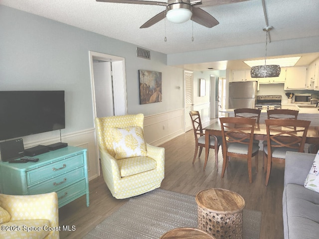 504 Fillmore Ave Unit B-8, Cape Canaveral, FL 32920 - living area with wood finished floors, wainscoting, a ceiling fan, and a textured ceiling