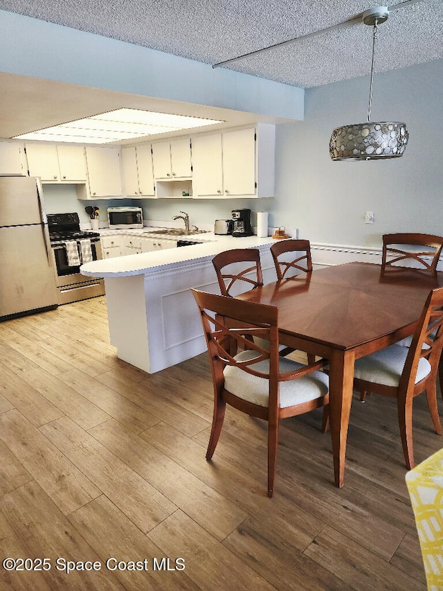 504 Fillmore Ave Unit B-8, Cape Canaveral, FL 32920 - kitchen with appliances with stainless steel finishes, a peninsula, light countertops, a textured ceiling, and a sink