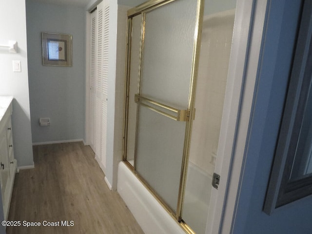 504 Fillmore Ave Unit B-8, Cape Canaveral, FL 32920 - full bathroom featuring wood finished floors, vanity, baseboards, and shower / bath combination with glass door