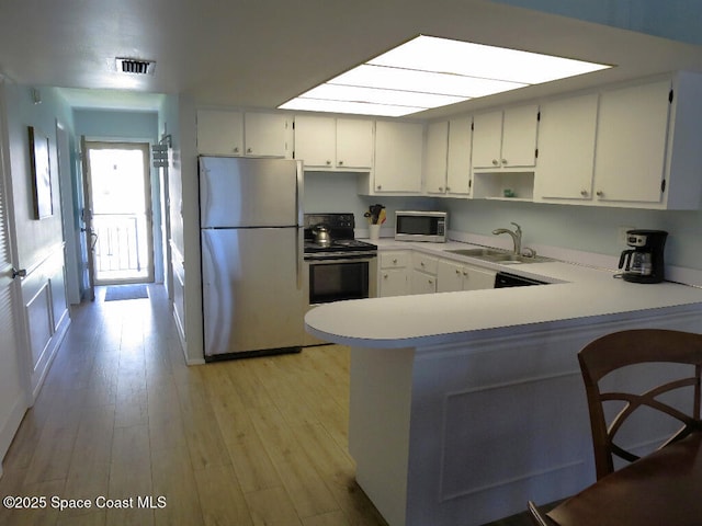504 Fillmore Ave Unit B-8, Cape Canaveral, FL 32920 - kitchen with freestanding refrigerator, stainless steel microwave, electric range, a sink, and light wood-type flooring