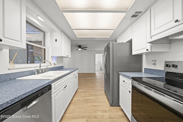 2036 Hogan Dr, Melbourne, FL 32935 - kitchen with stainless steel appliances, a sink, light wood finished floors, and white cabinetry