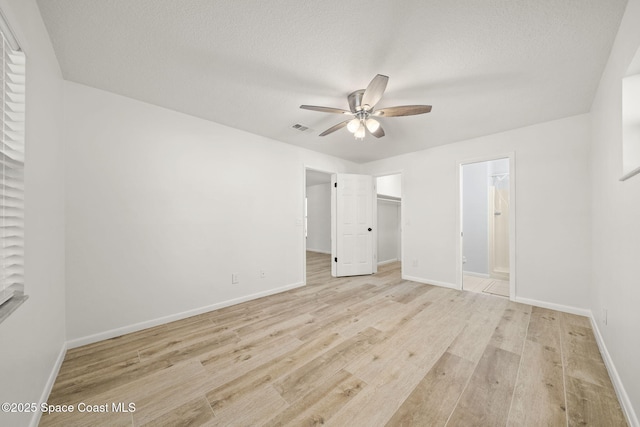 2036 Hogan Dr, Melbourne, FL 32935 - unfurnished bedroom featuring light wood-type flooring, a spacious closet, baseboards, ensuite bath, and ceiling fan