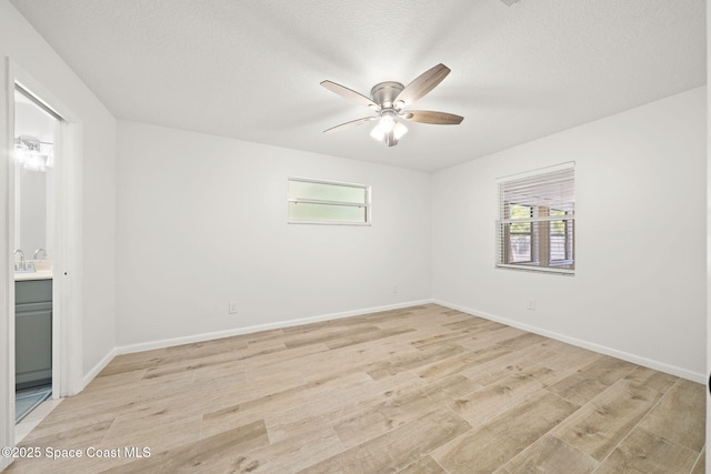 2036 Hogan Dr, Melbourne, FL 32935 - unfurnished room featuring healthy amount of natural light, ceiling fan, light wood finished floors, baseboards, and a textured ceiling