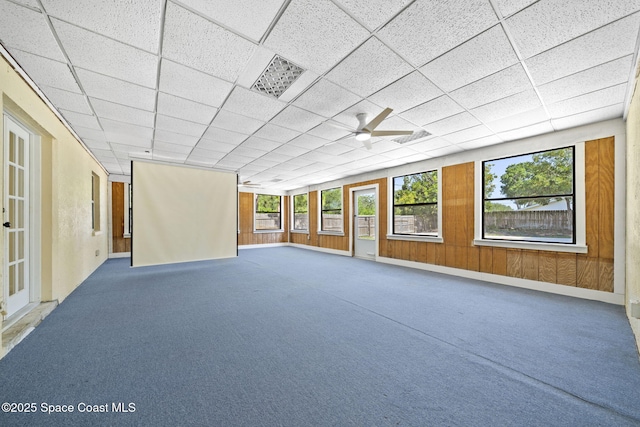 2036 Hogan Dr, Melbourne, FL 32935 - empty room with plenty of natural light, a ceiling fan, wooden walls, and carpet floors
