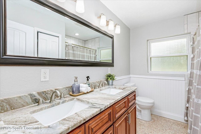 439 Blue Heron Rd, Melbourne Village, FL 32904 - full bathroom with wainscoting, double vanity, a shower with curtain, and speckled floor