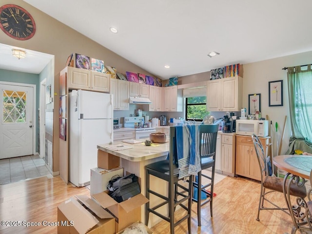 3625 2nd Ln, Vero Beach, FL 32968 - kitchen featuring white appliances, under cabinet range hood, light countertops, vaulted ceiling, and light wood-style flooring
