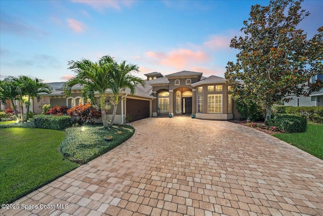 3311 Gatlin Dr, Rockledge, FL 32955 - mediterranean / spanish house with decorative driveway, an attached garage, a yard, and stucco siding