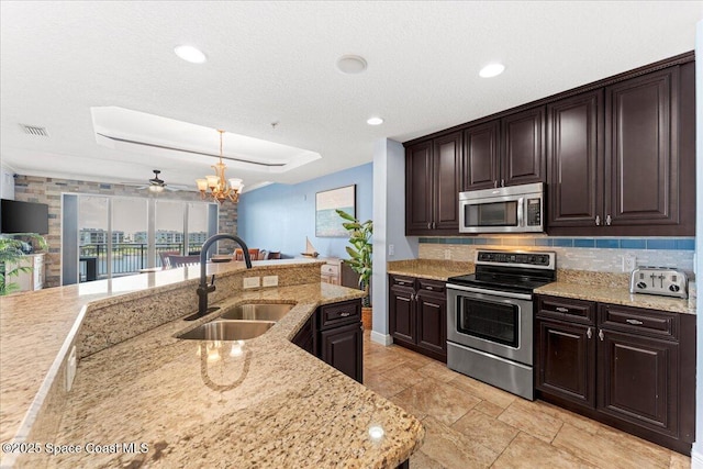 4125 W End Rd Unit 405, Cocoa Beach, FL 32931 - kitchen featuring appliances with stainless steel finishes, a sink, backsplash, dark brown cabinetry, and light stone counters