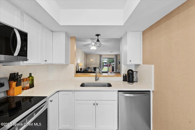 149 Kristi Dr, Indian Harbour Beach, FL 32937 - kitchen with appliances with stainless steel finishes, a sink, a ceiling fan, white cabinets, and a tray ceiling