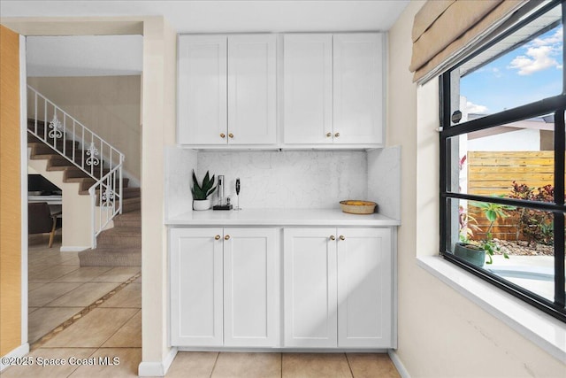 149 Kristi Dr, Indian Harbour Beach, FL 32937 - kitchen with white cabinets, backsplash, light countertops, light tile patterned floors, and baseboards