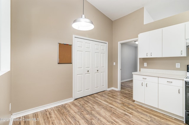 3220 Lowry Blvd SE, Palm Bay, FL 32909 - kitchen featuring light countertops, light wood-style flooring, white cabinets, baseboards, and a high ceiling