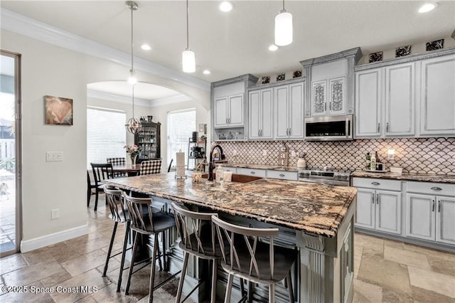 121 Amherst Ln, Sebastian, FL 32958 - kitchen featuring stainless steel appliances, baseboards, arched walkways, backsplash, and crown molding