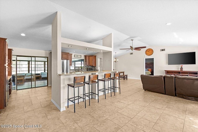 7020 Kaylor Ave, Cocoa, FL 32927 - kitchen featuring freestanding refrigerator, a ceiling fan, a kitchen breakfast bar, open floor plan, and vaulted ceiling