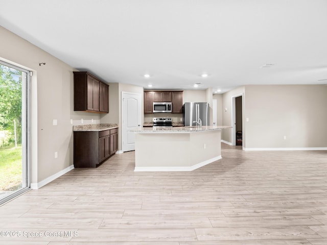 999 Zambrana St SE, Palm Bay, FL 32909 - kitchen with appliances with stainless steel finishes, light wood-style flooring, recessed lighting, dark brown cabinets, and a kitchen island with sink