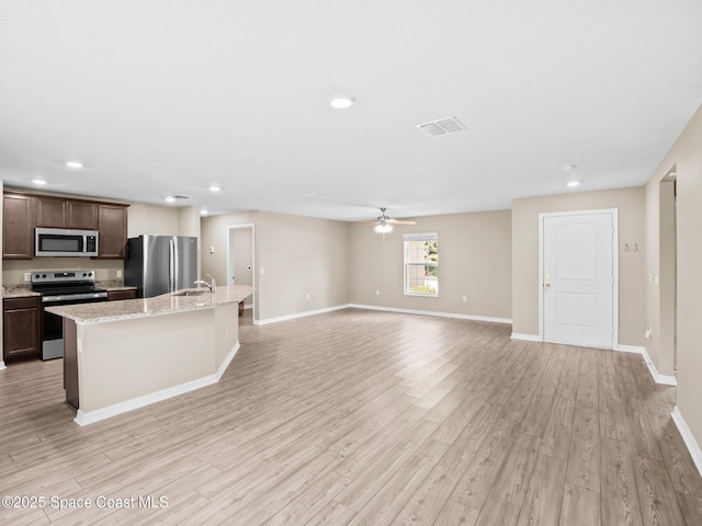 999 Zambrana St SE, Palm Bay, FL 32909 - kitchen featuring stainless steel appliances, a sink, light wood-style flooring, an island with sink, and baseboards