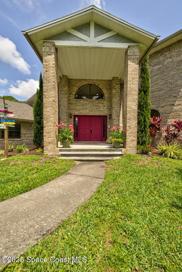 4956 Corfu Dr, Cocoa, FL 32926 - doorway to property with brick siding, a yard, and a porch