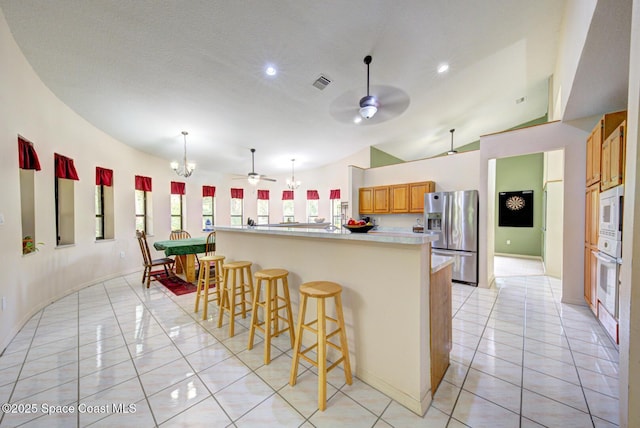 4956 Corfu Dr, Cocoa, FL 32926 - kitchen featuring white appliances, a ceiling fan, light tile patterned floors, a breakfast bar area, and light countertops