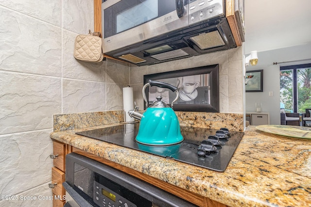 403 Seaport Blvd Unit T145, Cape Canaveral, FL 32920 - detailed view of stainless steel microwave, tasteful backsplash, and black electric cooktop