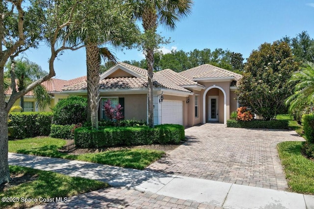 5209 Eleuthra Cir, Vero Beach, FL 32967 - mediterranean / spanish-style house featuring an attached garage, stucco siding, a tiled roof, and driveway