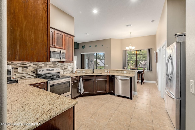 4725 Papaya St, Cocoa, FL 32926 - kitchen featuring appliances with stainless steel finishes, a peninsula, tasteful backsplash, a sink, and light stone countertops