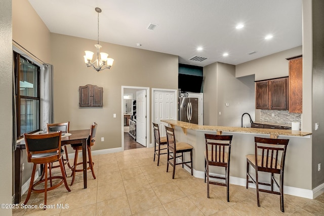 4725 Papaya St, Cocoa, FL 32926 - kitchen featuring freestanding refrigerator, a peninsula, a chandelier, a breakfast bar area, and tasteful backsplash