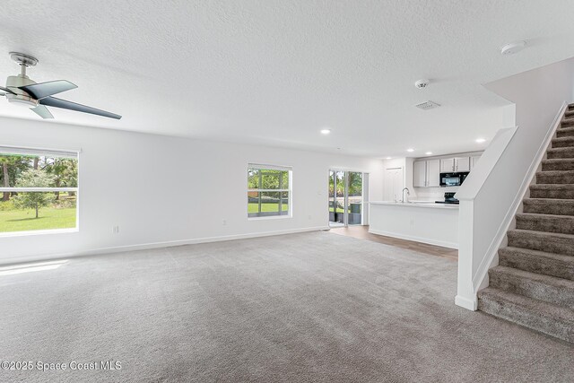 2205 Sapelo Ave SE, Palm Bay, FL 32909 - unfurnished living room with stairs, plenty of natural light, ceiling fan, light carpet, and recessed lighting