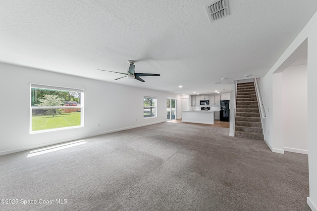 2205 Sapelo Ave SE, Palm Bay, FL 32909 - unfurnished living room with ceiling fan, light carpet, stairway, baseboards, and a textured ceiling