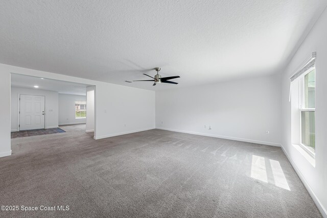 2205 Sapelo Ave SE, Palm Bay, FL 32909 - unfurnished living room with ceiling fan, carpet floors, a textured ceiling, and baseboards