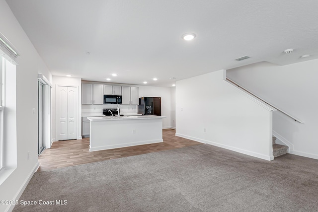 2205 Sapelo Ave SE, Palm Bay, FL 32909 - kitchen with black appliances, light colored carpet, recessed lighting, baseboards, and light countertops