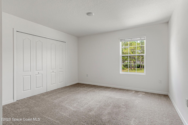 2205 Sapelo Ave SE, Palm Bay, FL 32909 - unfurnished bedroom featuring a textured ceiling, carpet floors, a closet, and baseboards
