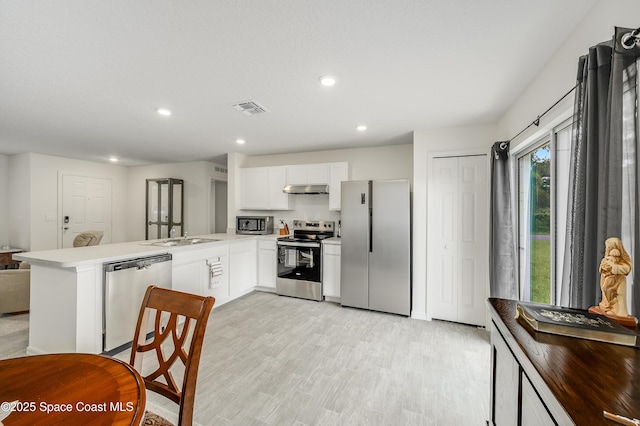 499 Grenadier Ave NW, Palm Bay, FL 32907 - kitchen featuring appliances with stainless steel finishes, under cabinet range hood, a peninsula, white cabinetry, and recessed lighting