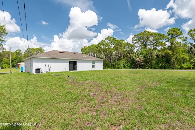 499 Grenadier Ave NW, Palm Bay, FL 32907 - back of property featuring central air condition unit, stucco siding, a lawn, and view of scattered trees